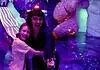 Factory Obscura’s RECORD+PLAY adds new layers of interaction to Mix-Tape Two people hug and smile in a neon-lit, immersive art space with colorful glowing sculptures behind them, purple lighting everywhere.