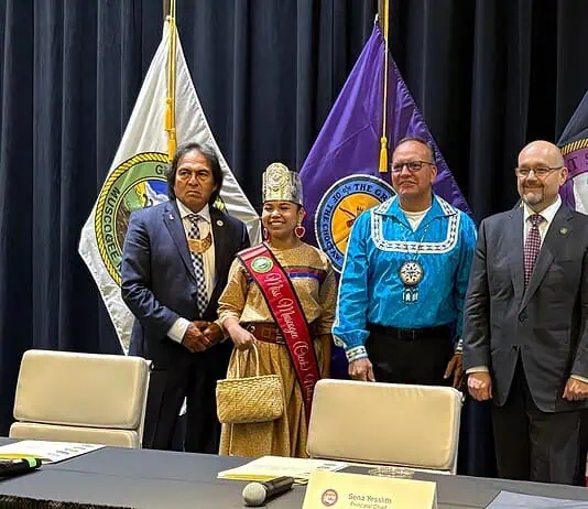 PRESS RELEASE: Five Tribes call for oversight of prediction markets Six people in formal attire stand on a stage with colorful banners and flags behind them, posing for a group photo.