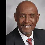 PRESS RELEASE: OKC honors the life of M.T. Berry, first Black police chief Professional headshot of a smiling Black man in a dark pinstripe suit and red patterned tie, against a gray backdrop.
