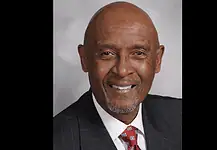 PRESS RELEASE: OKC honors the life of M.T. Berry, first Black police chief Professional headshot of a smiling Black man in a dark pinstripe suit and red patterned tie, against a gray backdrop.