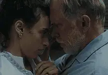 Hypnotic, unsettling ‘Night Nurse’ a piercing portrait of sociopathy Young woman and an older man press foreheads together in a tender, intimate moment beside a wall.