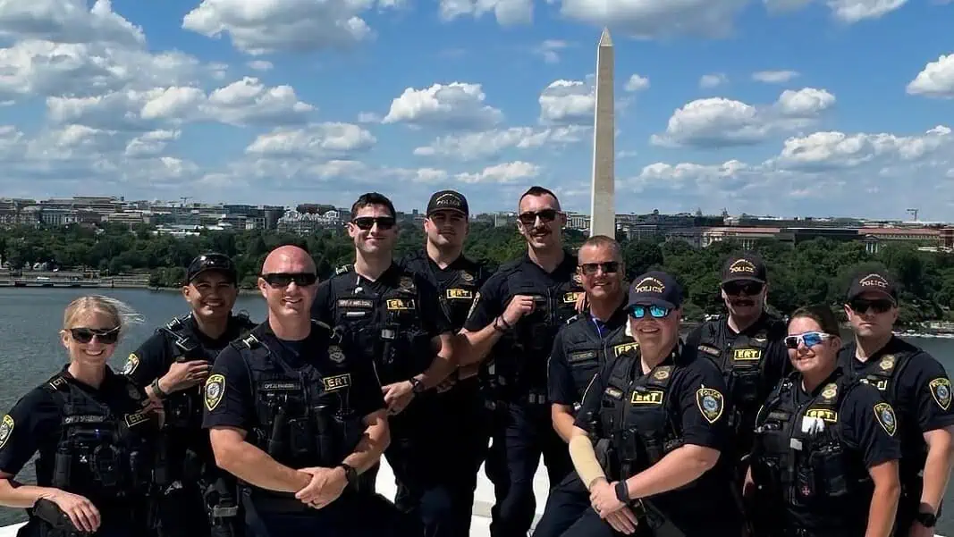 OKC police in DC (from facebook) Group of police officers posing for a photo on a boat or dock with the Washington Monument in the background along the Potomac River