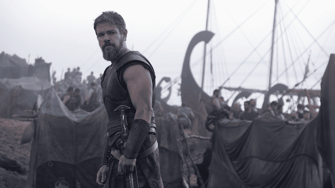 Odyssey 10 Bearded warrior in dark armor stands at the edge of a tents-filled camp with ships and masts in the misty background.