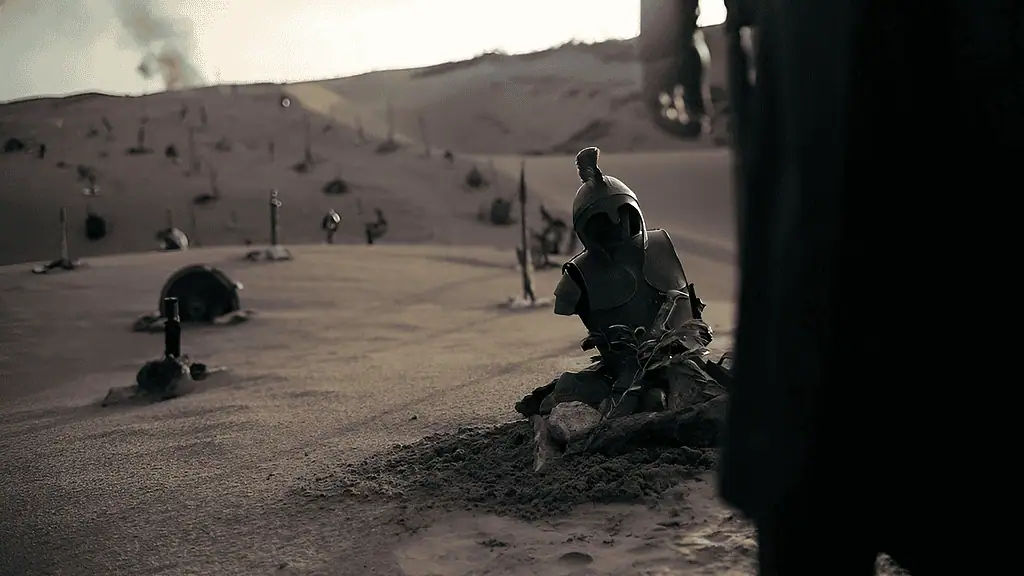 Dusty desert landscape with scattered armor pieces and a blue helmet perched on rocks in the sand.
