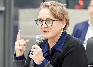 Paula Lewis resigns from Oklahoma City school board after historic tenure Woman with glasses speaking into a microphone during a panel discussion in a conference setting.