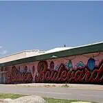 PRESS RELEASE: Residents invited to help shape the future of the Classen Corridor Clear blue sky over a street with a long mural spelling 'Boardwalk' along a pink-walled building.