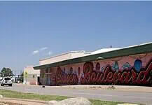 PRESS RELEASE: Residents invited to help shape the future of the Classen Corridor Clear blue sky over a street with a long mural spelling 'Boardwalk' along a pink-walled building.