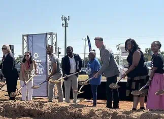 Clara Luper Civil Rights Center celebrates long-awaited groundbreaking Diverse group at a groundbreaking ceremony, each person with a shovel poised to dig on a dirt mound, banners in background.