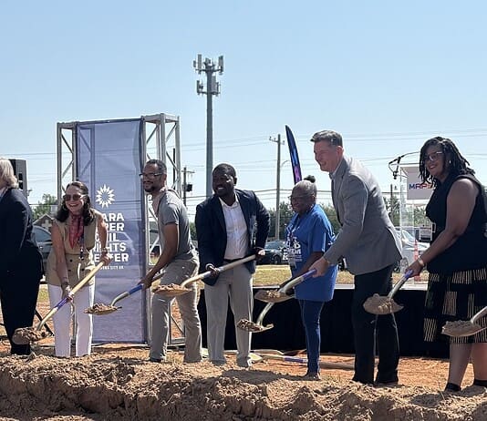 Clara Luper Civil Rights Center celebrates long-awaited groundbreaking Diverse group at a groundbreaking ceremony, each person with a shovel poised to dig on a dirt mound, banners in background.