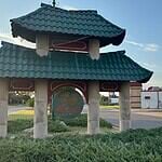 Police host public discussion over homelessness, crime in Asian District Pagoda-style shelter with a teal, wavy roof over a circular 'Asian' sign on a grassy median by the road.