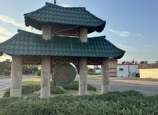 Police host public discussion over homelessness, crime in Asian District Pagoda-style shelter with a teal, wavy roof over a circular 'Asian' sign on a grassy median by the road.