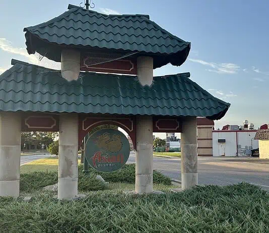 Police host public discussion over homelessness, crime in Asian District Pagoda-style shelter with a teal, wavy roof over a circular 'Asian' sign on a grassy median by the road.