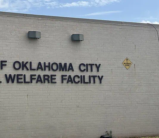 Poor health among 500 rescued animals; cruelty charges incoming Exterior wall with the sign 'City of Oklahoma City Animal Welfare Facility' and a nearby oxygen warning sign on the right; utility cabinet on the left against a blue sky backdrop.