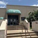 City forced to euthanize 250 birds seized in June drug bust Entrance to a beige building with green curved awnings, concrete stairs, and metal railings under a blue sky.