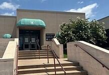 City forced to euthanize 250 birds seized in June drug bust Entrance to a beige building with green curved awnings, concrete stairs, and metal railings under a blue sky.