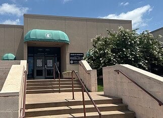 City forced to euthanize 250 birds seized in June drug bust Entrance to a beige building with green curved awnings, concrete stairs, and metal railings under a blue sky.