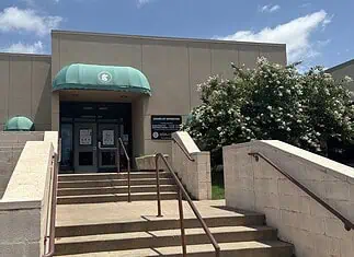 City forced to euthanize 250 birds seized in June drug bust Entrance to a beige building with green curved awnings, concrete stairs, and metal railings under a blue sky.