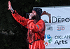 Bring the power of OK’s live music into your home with these new drops Male performer in a red jumpsuit sings into a microphone on an outdoor stage, with an arts banner in the background.
