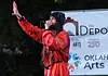 Bring the power of OK’s live music into your home with these new drops Male performer in a red jumpsuit sings into a microphone on an outdoor stage, with an arts banner in the background.