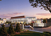 Exterior view of the Woodson Park community center at sunset, with cars parked and people walking toward a landscaped entrance.