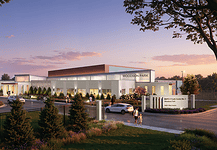 Exterior view of the Woodson Park community center at sunset, with cars parked and people walking toward a landscaped entrance.