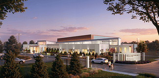 Exterior view of the Woodson Park community center at sunset, with cars parked and people walking toward a landscaped entrance.