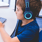 An all-AI private school with no teachers is set to open in Edmond Child wearing blue headphones typing on a Dell laptop at a white table in a classroom or study area