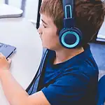 An all-AI private school with no teachers is set to open in Edmond Child wearing blue headphones typing on a Dell laptop at a white table in a classroom or study area