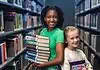 PRESS RELEASE: Summer reading, screen-free fun, and romance authors await in July events at Metro Library Two smiling girls stand in a library aisle, one holding a stack of colorful books for reading and sharing.