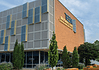 Poor defendants often blocked from OK County pretrial release program Modern brick building with a grey panel facade and blue-yellow decorative panels; a sign on the brick wall reads Transformation Center, with glass windows and trees in front.