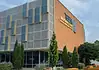 Poor defendants often blocked from OK County pretrial release program Modern brick building with a grey panel facade and blue-yellow decorative panels; a sign on the brick wall reads Transformation Center, with glass windows and trees in front.