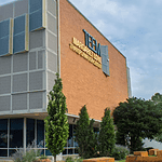 Poor defendants often blocked from OK County pretrial release program Modern brick building with a grey panel facade and blue-yellow decorative panels; a sign on the brick wall reads Transformation Center, with glass windows and trees in front.