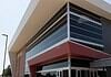 Modern glass-fronted commercial building with a bold red entrance canopy and brick side wall.