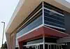 OKCPS celebrates opening of new $116 million Capitol Hill High School Modern glass-fronted commercial building with a bold red entrance canopy and brick side wall.