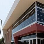 Modern glass-fronted commercial building with a bold red entrance canopy and brick side wall.