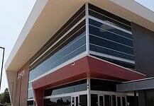 Modern glass-fronted commercial building with a bold red entrance canopy and brick side wall.