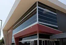 OKCPS celebrates opening of new $116 million Capitol Hill High School Modern glass-fronted commercial building with a bold red entrance canopy and brick side wall.