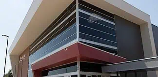 Modern glass-fronted commercial building with a bold red entrance canopy and brick side wall.