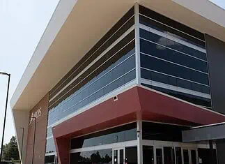 OKCPS celebrates opening of new $116 million Capitol Hill High School Modern glass-fronted commercial building with a bold red entrance canopy and brick side wall.