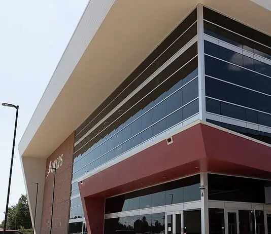 OKCPS celebrates opening of new $116 million Capitol Hill High School Modern glass-fronted commercial building with a bold red entrance canopy and brick side wall.
