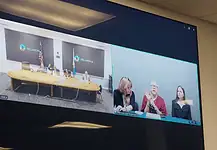 State executes longtime death row inmate convicted in OKC murder Split-screen video conference of a government meeting: left panel shows officials at a long table with flags in an Oklahoma setting; right panel shows three women, one signing, at a different location.
