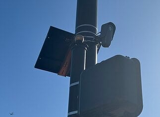 City to vote on sweeping ‘guardrails’ for Flock cameras as OKCPD continues use Streetlight pole with a solar panel, security camera, and large control box against a blue sky.