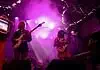 Catch these scene-leading locals opening for can’t-miss nationals across OKC Band performing on a lit stage with purple lights; two guitarists and a keyboard player, drum kit in back, vintage TV on a red pedestal to the left.